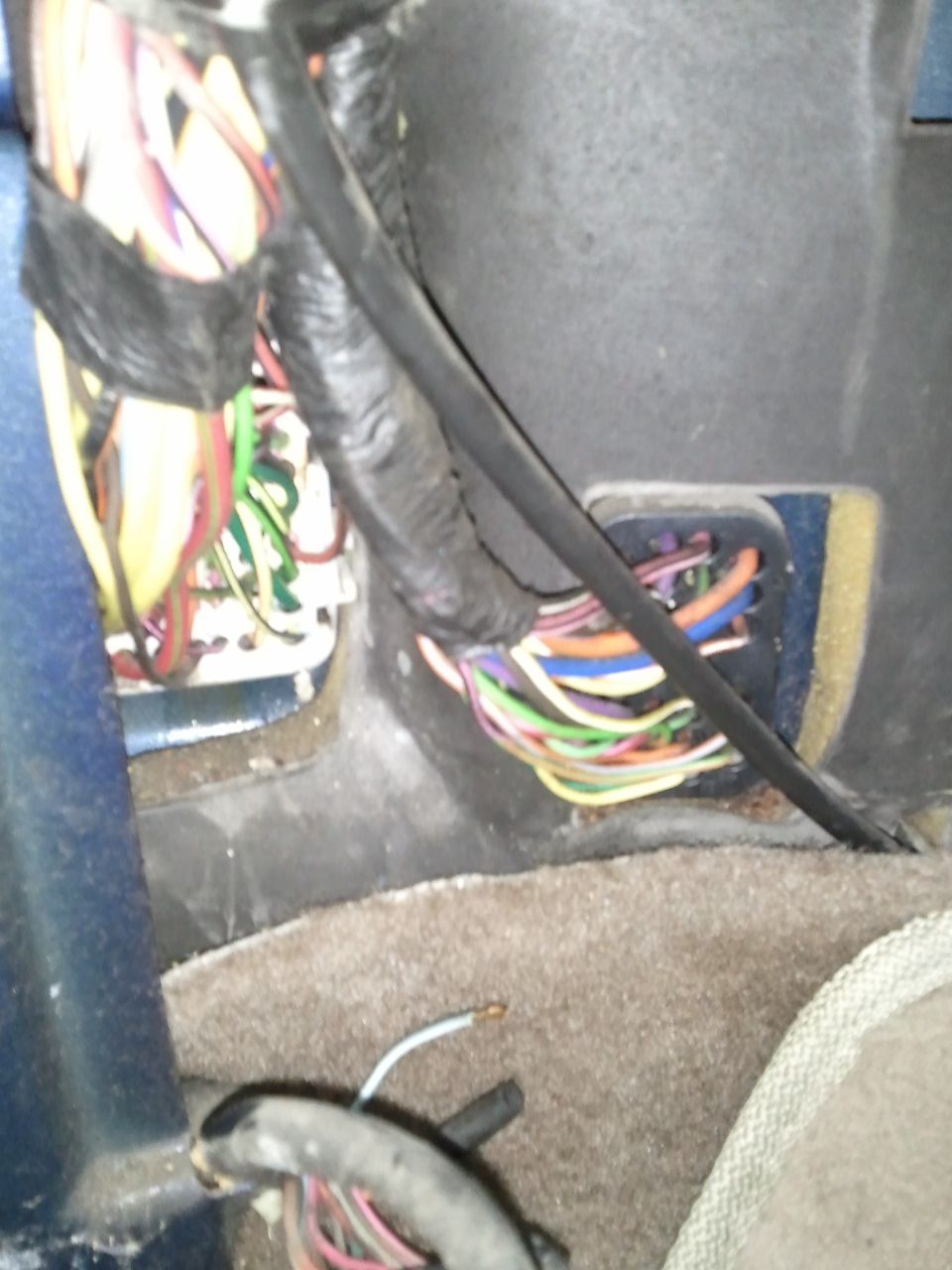 Close-up of a vehicle's interior wiring harness with many colorful wires