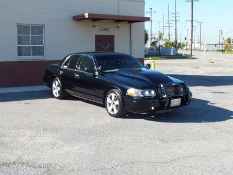 2003 Ford Crown Victoria - Black sedan from front right in daylight, brush guard and billet grille, lowered on polished wheels.