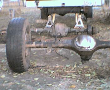 1984 Ford Bronco - Close-up of a vehicle's rear axle assembly, with a tire attached and the vehicle elevated on jack stands.
