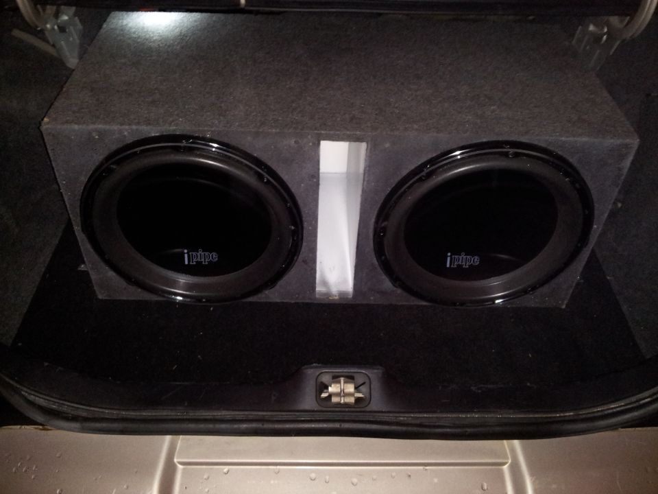 Dual iPIPE subwoofers in a carpeted box, seen in a car trunk