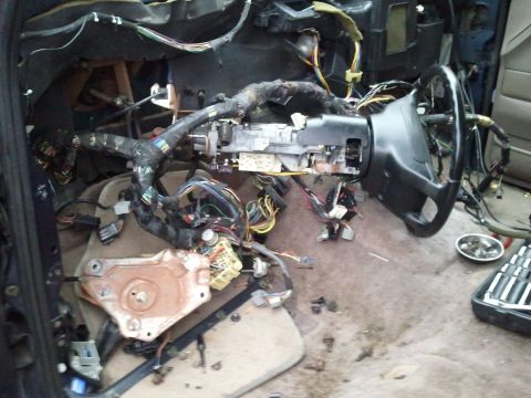 1994 Ford Bronco - The interior of a vehicle is shown with the dashboard removed, revealing complex wiring and the steering column.