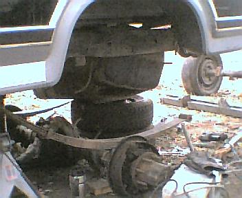 1984 Ford Bronco - Close-up of a vehicle's rear axle and suspension components, with a SuperMotors logo.