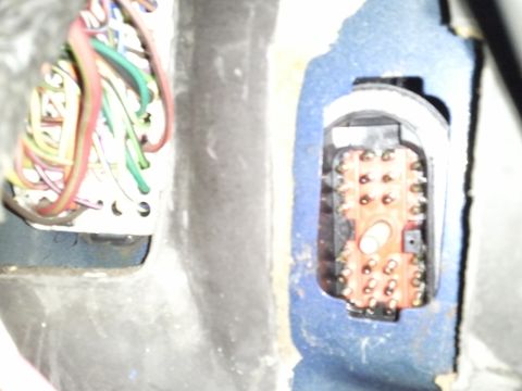 1994 Ford Bronco - A close-up view of a vehicle's interior wiring harness and an exposed connector with numerous pins.