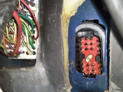 1994 Ford Bronco - Close-up of a vehicle's wiring harness and a red electrical connector with multiple pins, likely part of the dashboard's electrical system.