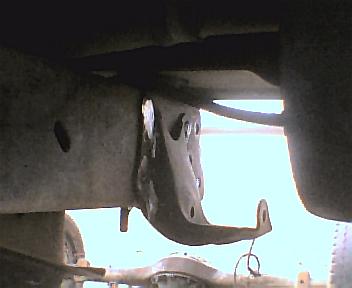 1984 Ford Bronco - A close-up view of a vehicle's frame and an attached metal bracket, with a website logo in the lower right corner.