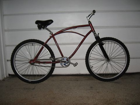 1994 Ford Bronco - A side view of a red cruiser bicycle with a black seat and tires, positioned against a white paneled background.