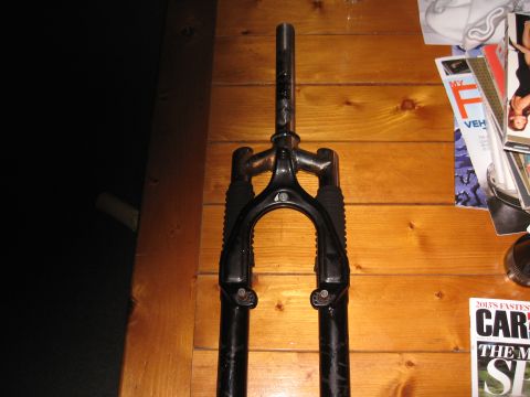 1994 Ford Bronco - A bicycle's front fork is shown against a wooden background, with magazines visible to the right.