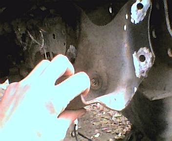 1984 Ford Bronco - Close-up of a vehicle's suspension part being touched by a hand.