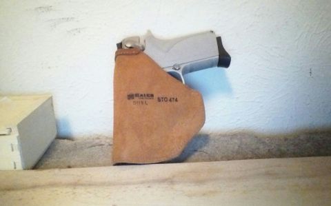 1993 Ford Bronco - A pistol rests in a leather holster against a textured wall.
