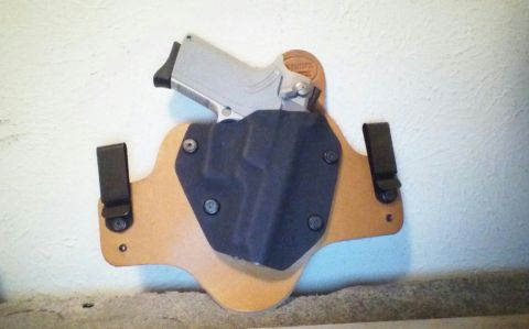 1993 Ford Bronco - A handgun is secured in a black holster mounted on a tan leather backing.