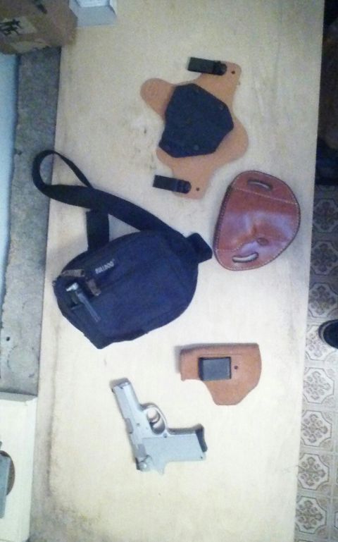 1993 Ford Bronco - A collection of firearm accessories, including a pistol, multiple holsters, and a shoulder bag, are laid out on a surface.