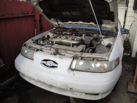 1992 Ford Taurus - Front view of a white 1992 Ford Taurus SHO with its hood open, revealing the engine compartment.