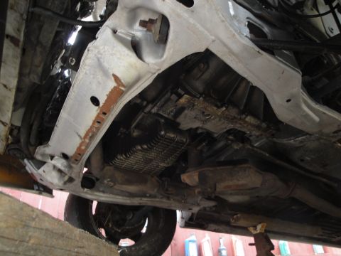 1992 Ford Taurus - Underside view of a vehicle's transmission, exhaust, and suspension components, showing signs of wear and rust.