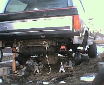 1984 Ford Bronco - The rear axle and suspension of a truck are visible as it is supported by jack stands.