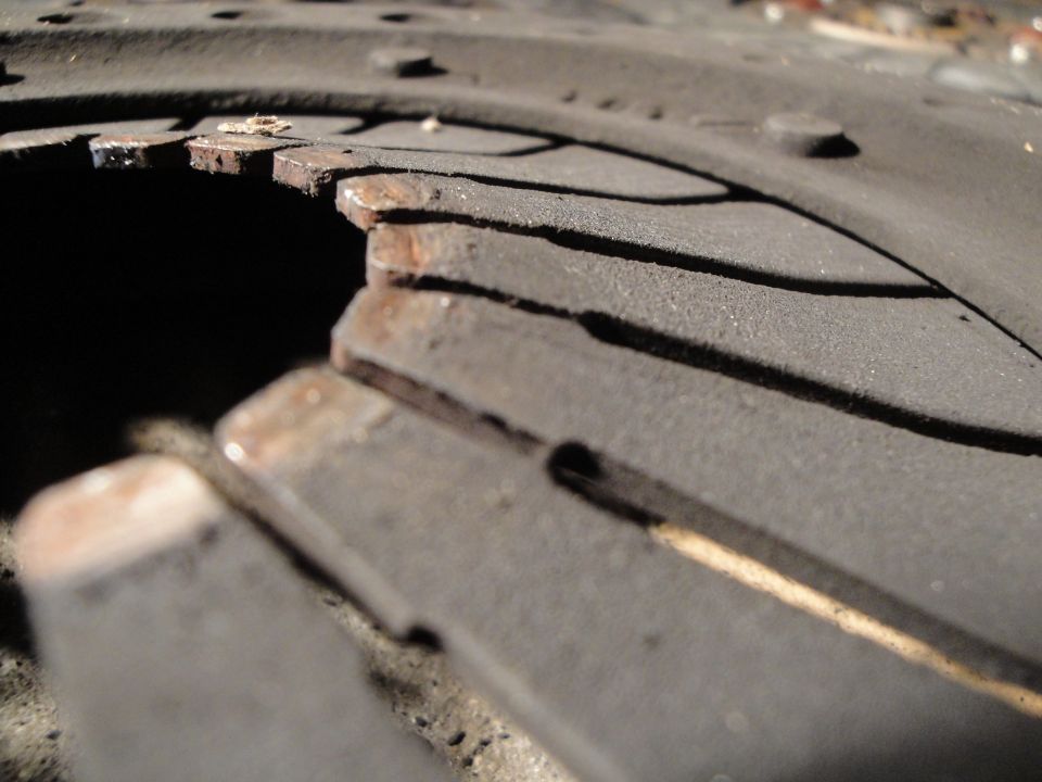 Close-up of a worn clutch disc with damaged friction material and exposed metal