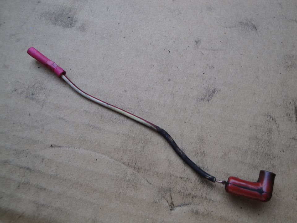 Wire with pink and white insulation, black protective sleeve, and a red boot connector