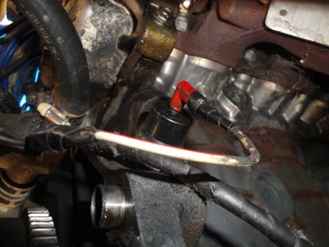 1992 Ford Taurus - Engine sensor and associated wiring, showing a black sensor with a red connector and electrical tape.