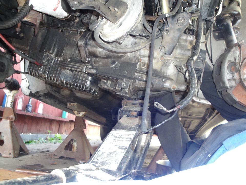 vehicle transmission and oil pan supported by jack stands and a floor jack