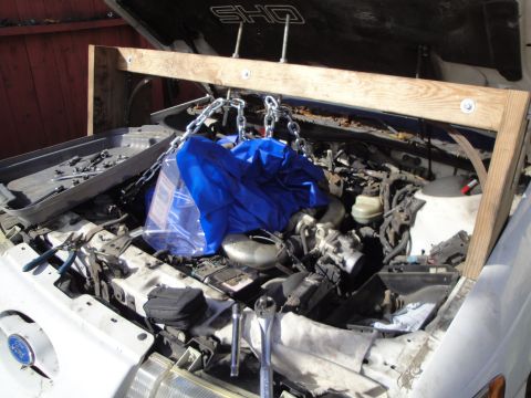 1992 Ford Taurus - Engine bay of a 1992 Ford Taurus SHO, equipped with an engine hoist and various tools for repair.