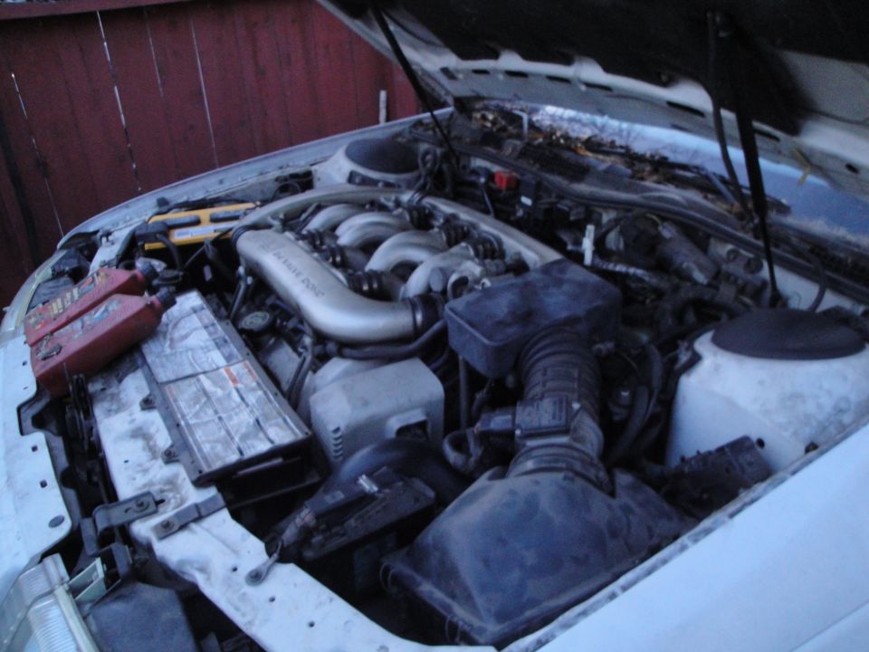 1992 Ford Taurus engine bay with hood open, showing V6 engine, battery, and fluid bottles