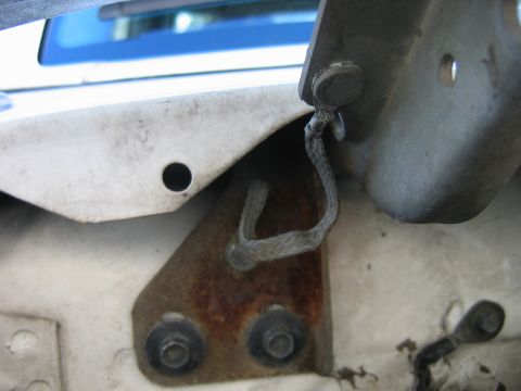 1992 Ford Bronco - A close-up view of a worn wiring harness connected to a bracket, showing signs of rust and wear.