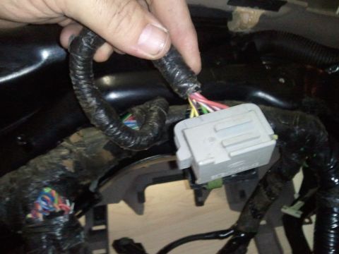 1994 Ford Bronco - A hand is shown connecting a wiring harness plug within a vehicle's dashboard area.