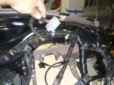 1994 Ford Bronco - Close-up of a car's dashboard wiring harness, showing complex electrical connections and a hand holding a connector.