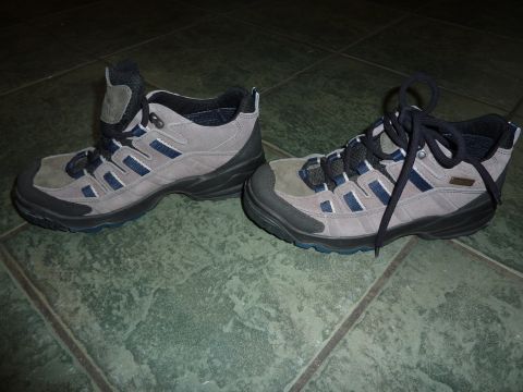 1900 Yugo GVX - These hiking boots are gray with blue accents and black laces, resting on a green tiled surface.