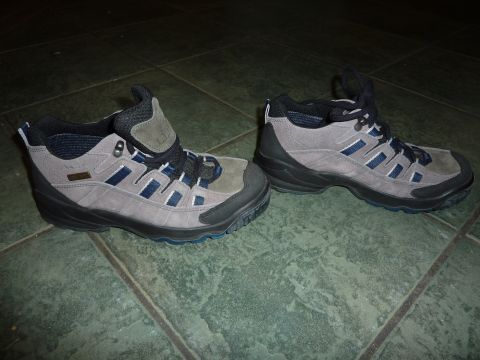 1900 Yugo GVX - A pair of gray and blue hiking boots are displayed on a dark tiled floor with a watermark in the corner.
