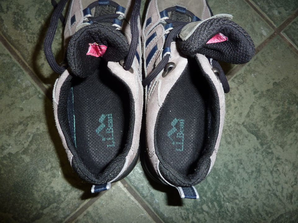 Pair of gray and blue athletic shoes with black laces, viewed from above, showing the insoles with a logo