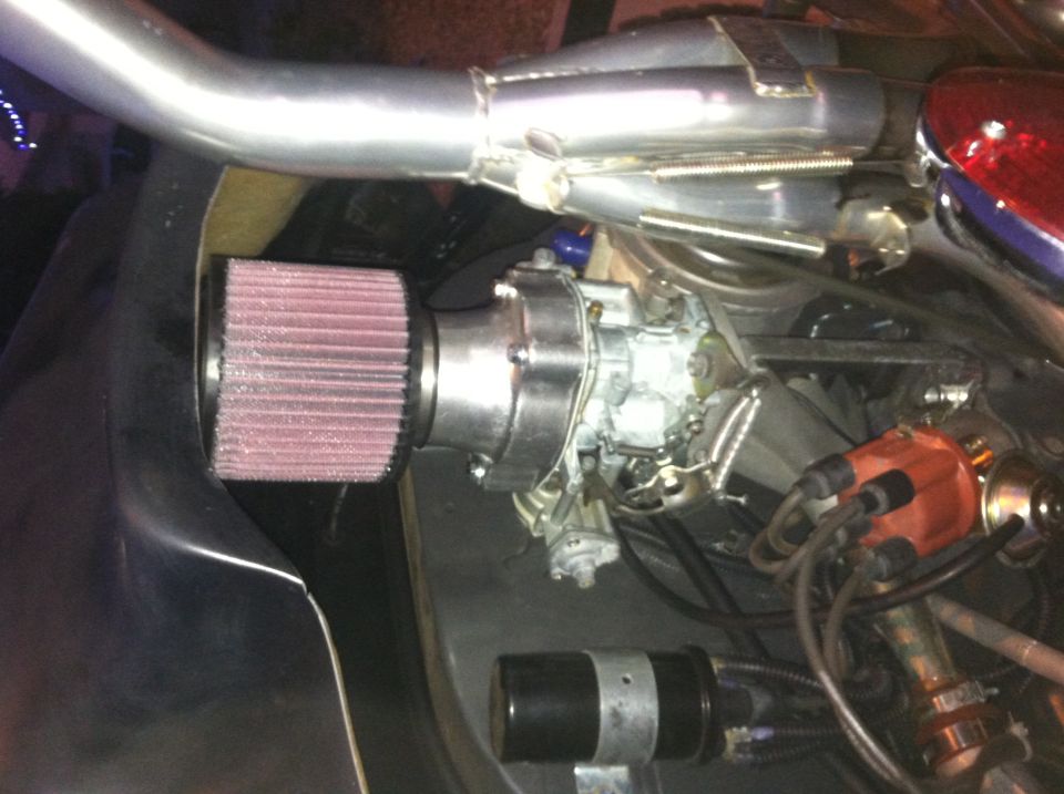 Engine bay with a large aftermarket air filter connected to the carburetor. Exhaust pipe is visible
