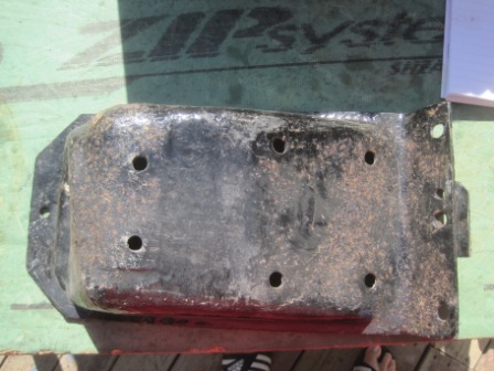 1993 Ford Bronco - A close-up view of a metal bracket, likely a vehicle part, with visible rust and bolt holes.