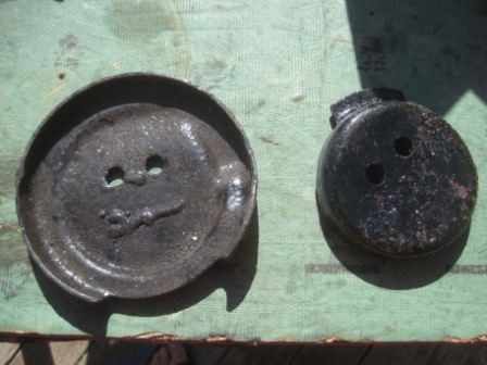 1993 Ford Bronco - Two unidentified metal automotive parts are displayed on a green surface.