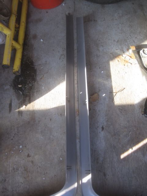 1993 Ford Bronco - Two gray trim pieces for a car door are shown on a concrete surface.
