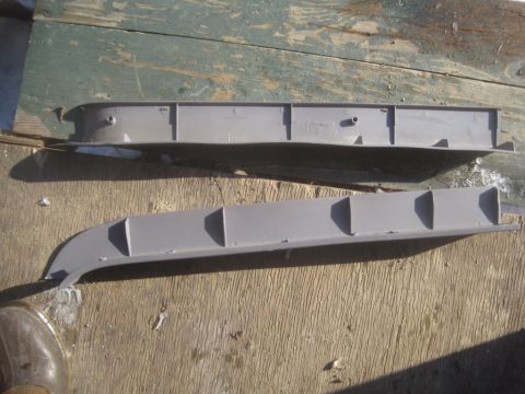 1993 Ford Bronco - Two gray plastic trim pieces are shown laid out on a weathered wooden surface.