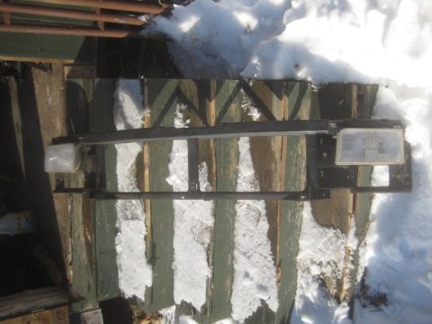 1993 Ford Bronco - This vehicle part, consisting of headlights and a grille support, is laid out on a wooden surface covered in snow.