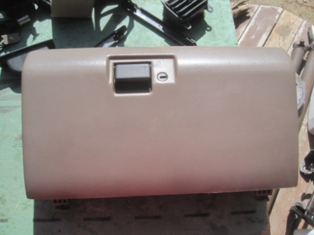 1993 Ford Bronco - This is a tan glove box door with a gray latch and a keyhole, likely for an older vehicle.