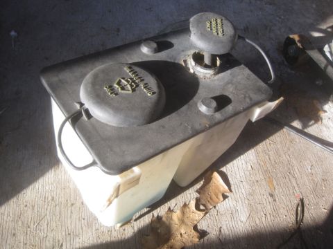 1993 Ford Bronco - A plastic windshield washer fluid reservoir sits on a concrete surface.