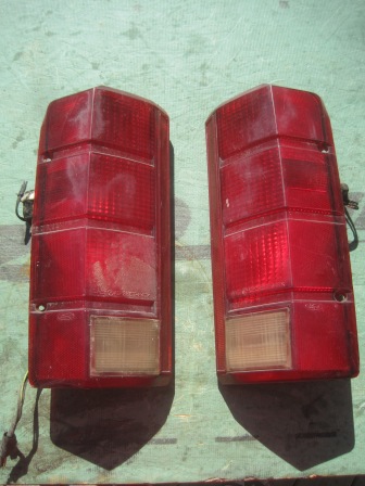 1993 Ford Bronco - A pair of red taillights are displayed against a textured background, with a website watermark at the bottom.