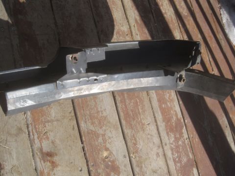 1993 Ford Bronco - A damaged metal bumper part is shown on a wooden surface, with visible mounting brackets and wear.