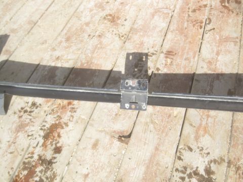 1993 Ford Bronco - Metal bracket and bar assembly on wooden planks, likely a vehicle part.