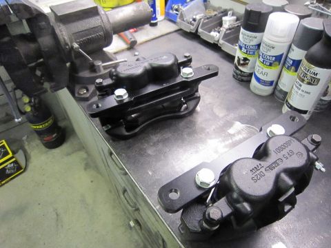 2008 Jeep Wrangler - New brake calipers and brackets are laid out on a workbench, ready for installation.