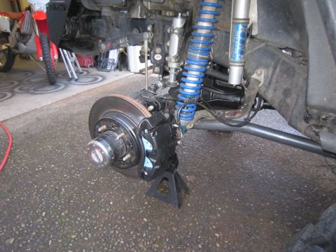 2008 Jeep Wrangler - Close-up of a vehicle's front brake assembly and suspension components, including a blue coilover shock absorber.