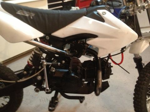 2003 Ford Crown Victoria - Close-up side view of a dirt bike's engine and frame, showing the black seat and white bodywork.