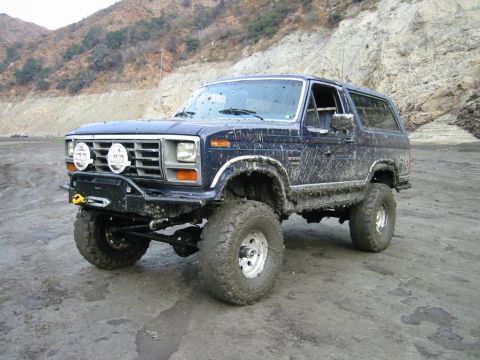 1985 Ford Bronco - This heavily modified Ford Bronco is covered in mud, suggesting it has been used for off-roading.