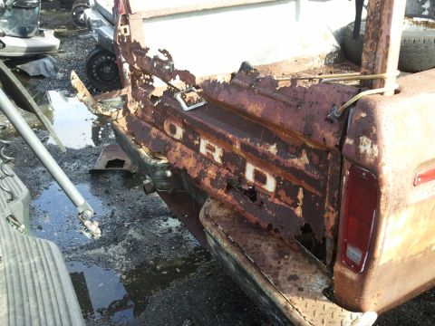 1994 Ford Bronco - This heavily rusted Ford truck tailgate displays significant damage and corrosion.