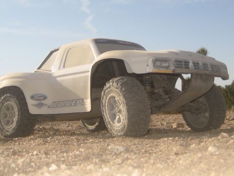 1996 Ford Bronco - This RC truck features Ford branding and JConcepts decals, presented in a 3/4 front view on a dirt terrain.