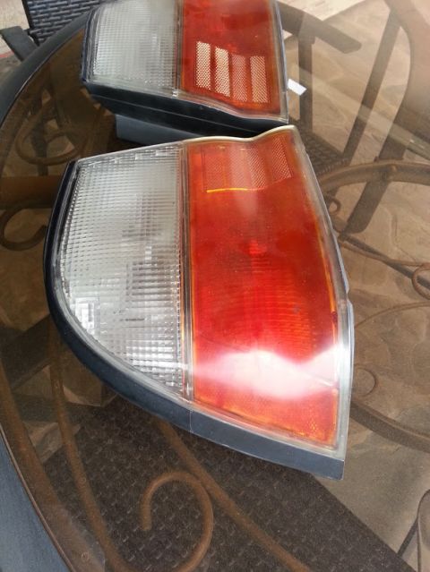 1978 Ford Bronco - Two vehicle taillights are shown on a glass table, with a watermark for Supermotors.net at the bottom right.