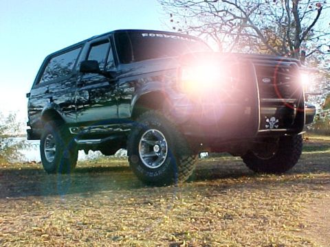 1995 Ford Bronco - This black Ford Bronco is parked outdoors near a body of water, with a skull and crossbones sticker on its front bumper.