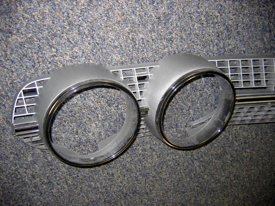 Car grille with two round headlight bezels. Supermotors.net logo at bottom right